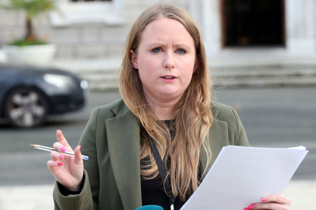 Mairéad Farrell - wearing a black top and green jacket - speaking outside Leinster House with paper in one hand and a pen in the other.