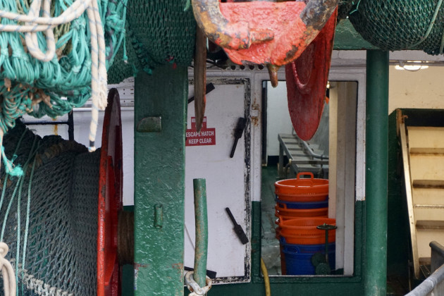 Large nets on reels with a view into the interior of a fishing vessels with plastic buckets inside an open door.
