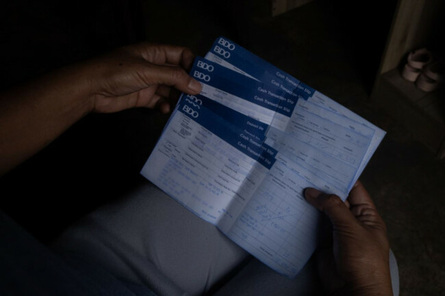 A woman holds banking slips in her hands with details blurred out to protect identity. 