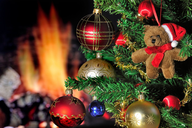 teddy-bear-and-bells-hanging-in-christmas-tree-in-front-of-hearth-fireplace