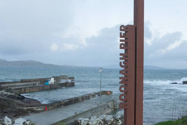 Metal sign for Roonagh Pier with the pier in the background