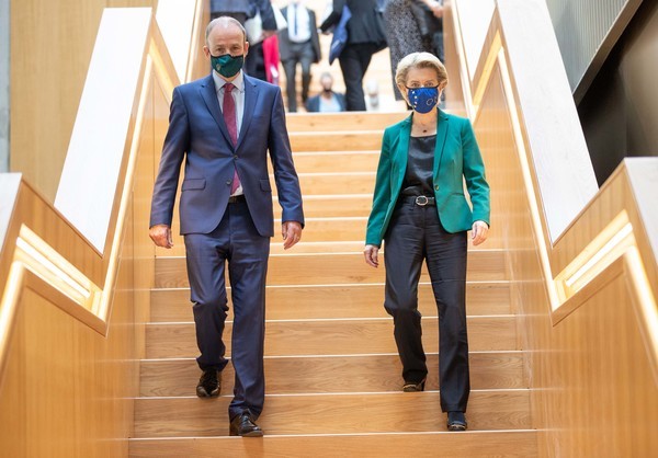 Then Taoiseach Micheál Martin and Ursula von der Leyen - both wearing business suits and face masks - walking down a wooden stairs.
