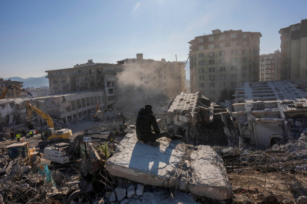 a-man-sits-atop-the-rubble-of-collapsed-buildings-during-the-earthquake-in-antakya-southeastern-turkey-tuesday-feb-14-2023-the-death-toll-from-the-earthquakes-of-feb-6-that-struck-turkey-and-n