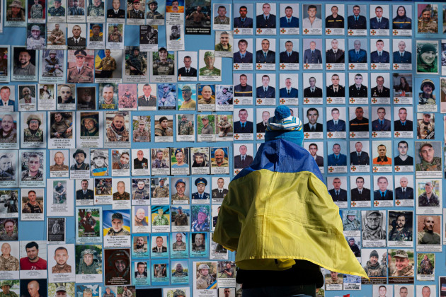 a-woman-wrapped-in-a-ukrainian-flag-stands-next-to-the-memory-wall-of-fallen-defenders-of-ukraine-in-russian-ukrainian-war-on-ukrainian-volunteer-day-in-kyiv-ukraine-tuesday-march-14-2023-ap-ph