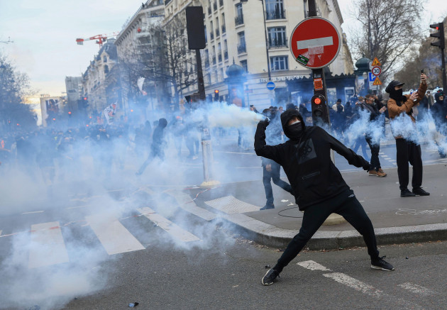 a-protester-throws-a-tear-gas-canister-as-he-scuffles-with-riot-police-during-a-rally-in-paris-thursday-march-23-2023-french-unions-are-holding-their-first-mass-demonstrations-thursday-since-presi