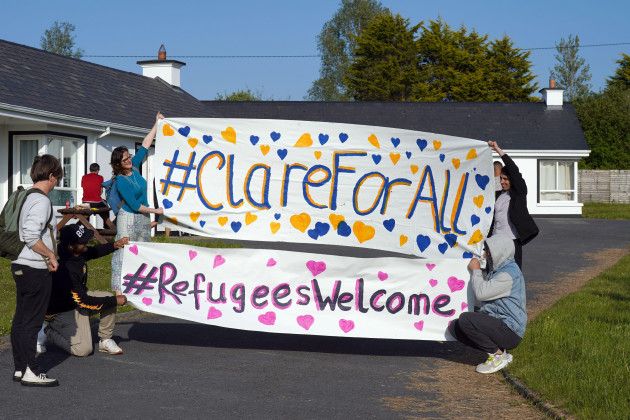 local-residents-with-asylum-seekers-hold-up-a-banner-supporting-refugees-as-other-locals-blockade-the-asylum-seeker-accommodation-at-the-magowna-house-hotel-in-inch-co-clare-the-residents-have-raise