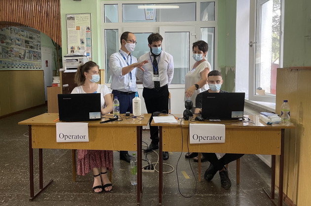 Members of an OSCE election observer team wearing facemasks observing election procedures at a polling station in Moldova in July 2021