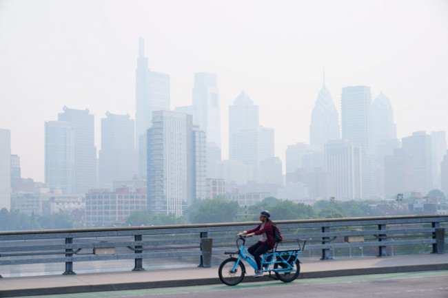 a-person-cycles-past-the-skyline-in-philadelphia-shrouded-in-haze-thursday-june-8-2023-intense-canadian-wildfires-are-blanketing-the-northeastern-u-s-in-a-dystopian-haze-turning-the-air-acrid-t
