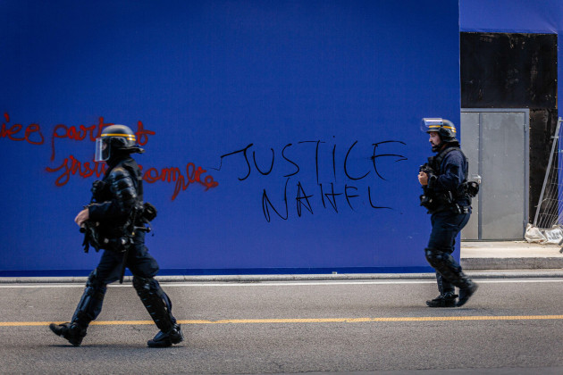 paris-france-30th-june-2023-two-police-officers-seen-passing-by-a-wall-with-justice-for-nahel-written-on-it-during-the-spontaneous-demonstration-on-the-fourth-day-of-protests-following-the-dea