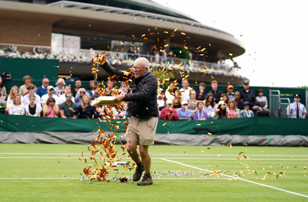 a-protester-on-court-18-throwing-confetti-on-to-the-grass-during-katie-boulters-first-round-match-against-daria-saville-on-day-three-of-the-2023-wimbledon-championships-at-the-all-england-lawn-tennis