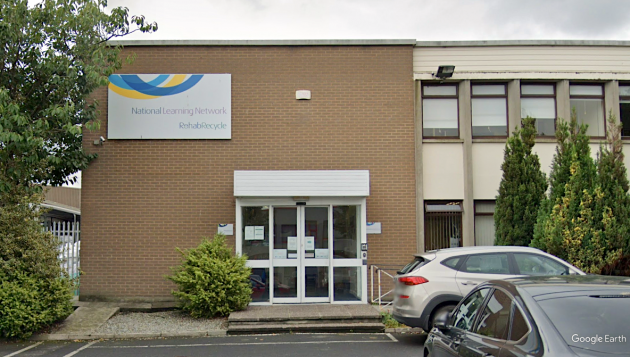 Entrance door to the building of Rehab Recycling, with a large sign with the company's name and logo.