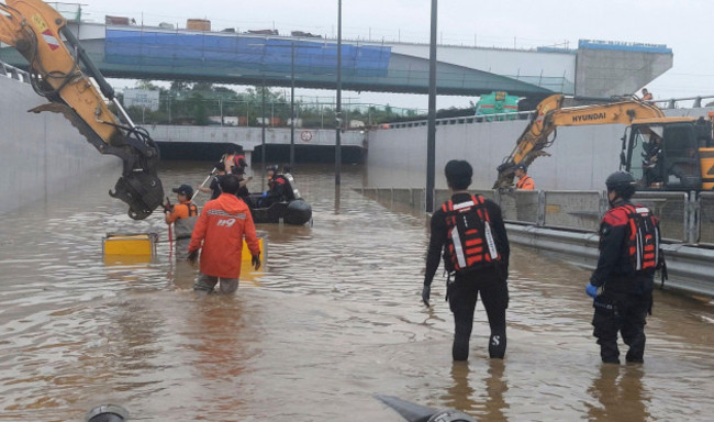 in-this-photo-provided-by-south-korea-national-fire-agency-rescuers-search-for-survivors-along-a-road-submerged-by-floodwaters-leading-to-an-underground-tunnel-in-cheongju-south-korea-sunday-july