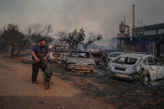 thanassis-barberakis-walks-with-his-dog-at-his-family-shipyard-damaged-from-the-fire-in-mandra-west-of-athens-on-tuesday-july-18-2023-in-greece-where-a-second-heatwave-is-expected-to-hit-thursday