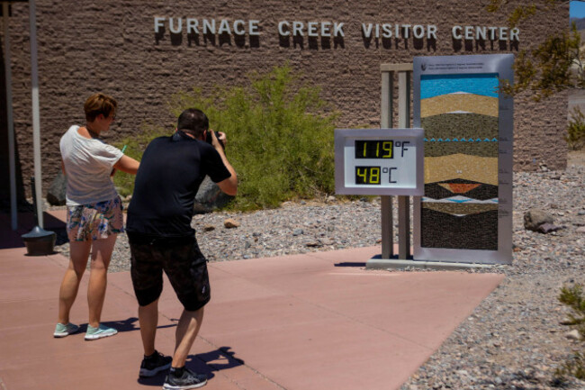 people-stop-to-take-photos-of-a-thermostat-reading-119-fahrenheit-48-celsius-at-the-furnace-creek-visitor-center-on-tuesday-july-11-2023-in-death-valley-national-park-calif-july-is