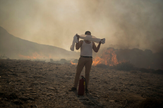 a-man-uses-towel-over-his-face-as-he-tries-to-extinguish-a-fire-near-the-seaside-resort-of-lindos-on-the-aegean-sea-island-of-rhodes-southeastern-greece-on-monday-july-24-2023-a-weeklong-wildfi