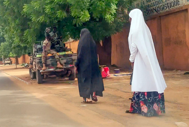 in-this-image-made-from-video-two-women-walk-past-soldiers-in-niamey-niger-friday-july-28-2023-the-general-who-led-a-coup-in-niger-defended-the-takeover-on-state-television-and-asked-for-support