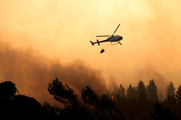 an-helicopter-discharges-water-on-the-flames-as-the-fire-advances-in-alcabideche-outside-lisbon-on-tuesday-july-25-2023-hundreds-of-firefighters-and-over-a-dozen-airplanes-were-fighting-a-wildfire