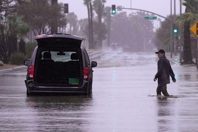 a-motorist-walks-out-to-remove-belongings-from-his-vehicle-after-becoming-stuck-in-a-flooded-street-sunday-aug-20-2023-in-palm-desert-calif-forecasters-said-tropical-storm-hilary-was-the-first