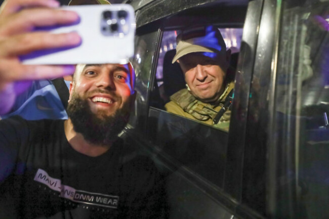 file-yevgeny-prigozhin-the-owner-of-the-wagner-group-military-company-right-sits-inside-a-military-vehicle-posing-for-a-photo-with-a-local-civilian-prior-to-leaving-an-area-of-the-hq-of-the-south