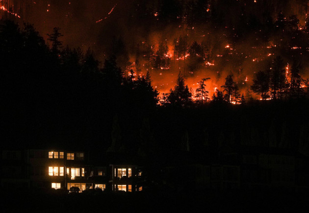 the-mcdougall-creek-wildfire-burns-on-the-mountainside-above-a-home-in-west-kelowna-b-c-on-friday-aug-18-2023-thousands-have-fled-driving-hundreds-of-kilometers-miles-to-safety-or-waiting-in