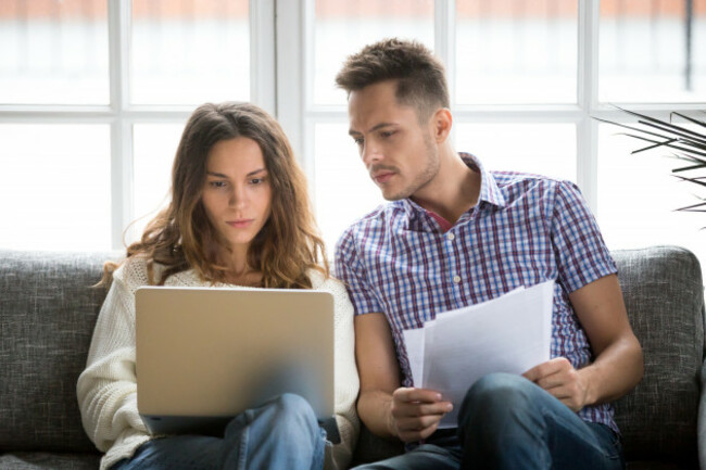 focusedworriedcouplepayingbillsonlineonlaptopwithdocuments