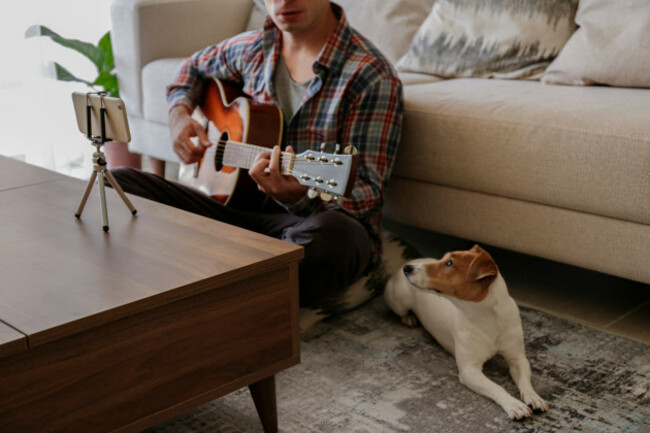 musicianpracticingacousticguitarexercisestakingonlinemusicalcoursesreading