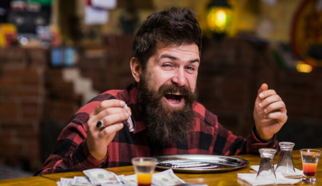 manwithcheerfulfacealoneatbarcountersniffingdrug