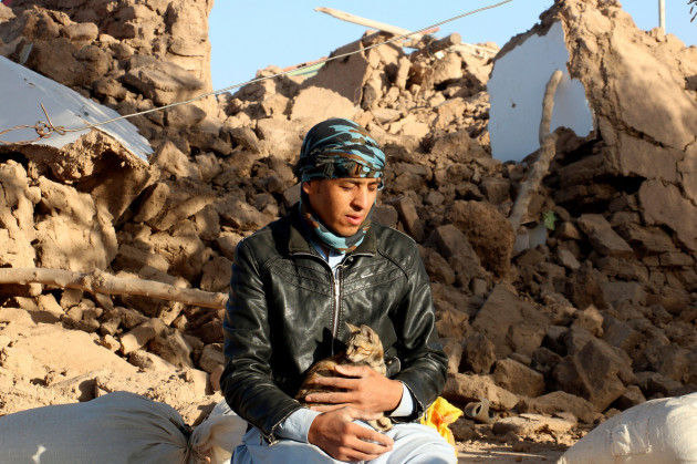 an-afghan-boy-hold-his-cat-as-he-sits-in-a-courtyard-of-his-destroyed-home-after-an-earthquake-in-zenda-jan-district-in-herat-province-of-western-afghanistan-sunday-oct-8-2023-powerful-earthqua