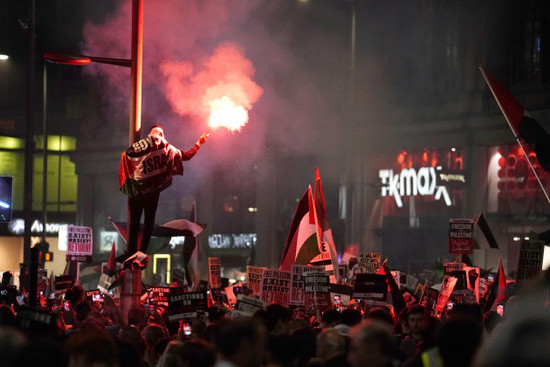 a-protester-climbs-a-lamp-post-as-people-take-part-in-a-palestine-solidarity-campaign-demonstration-near-the-israeli-embassy-in-kensingston-london-as-the-death-toll-rises-amid-ongoing-violence-in-i