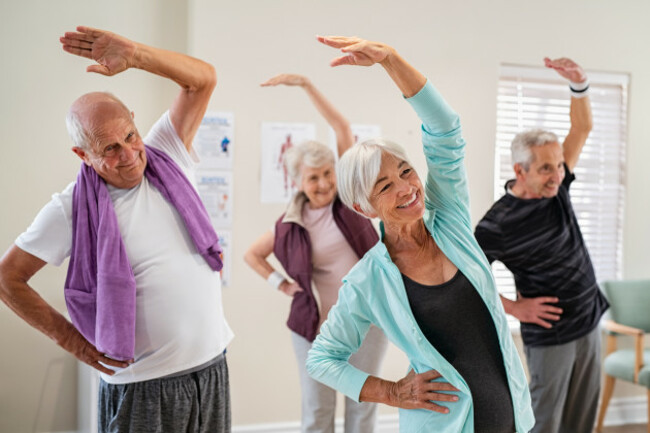 groupofseniorsdoingstretchingexercisetogetheratretirementcentre