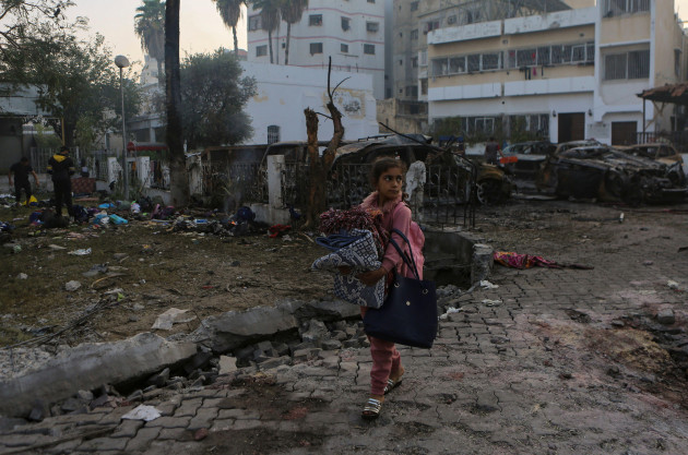 a-palestinian-girl-carries-a-blankets-as-she-walks-past-the-site-of-a-deadly-explosion-at-al-ahli-hospital-in-gaza-city-wednesday-oct-18-2023-the-hamas-run-health-ministry-says-an-israeli-airstr