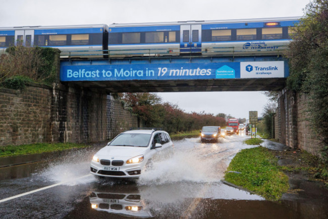 a-car-drives-through-a-flooded-area-under-a-railway-bridge-as-a-train-passes-overhead-on-the-a26-outside-the-village-of-moira-in-northern-ireland-picture-date-monday-october-30-2023