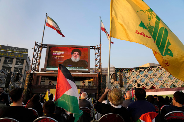 iranian-demonstrators-watch-a-speech-of-the-lebanons-militant-hezbollah-leader-sayyed-hassan-nasrallah-on-a-screen-as-one-of-them-holds-the-hezbollahs-flag-right-and-the-other-one-holds-a-palestin