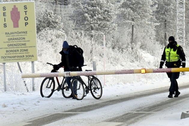 a-finnish-border-guard-looks-at-a-migrant-with-two-bicycles-at-the-international-border-crossing-at-salla-northern-finland-on-tuesday-nov-21-2023-finland-which-joined-nato-this-year-in-response