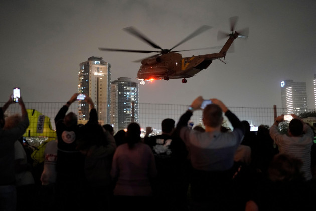 a-group-of-israelis-watch-as-a-helicopter-carrying-hostages-released-from-the-gaza-strip-lands-at-the-helipad-of-the-schneider-childrens-medical-center-in-petah-tikva-israel-sunday-nov-26-2023-t