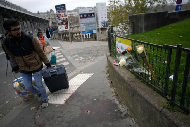 a-man-walks-past-flowers-placed-on-the-scene-where-a-man-targeted-passersbys-late-saturday-killing-a-german-tourist-with-a-knife-and-injuring-two-others-in-paris-sunday-dec-3-2023-police-subdued