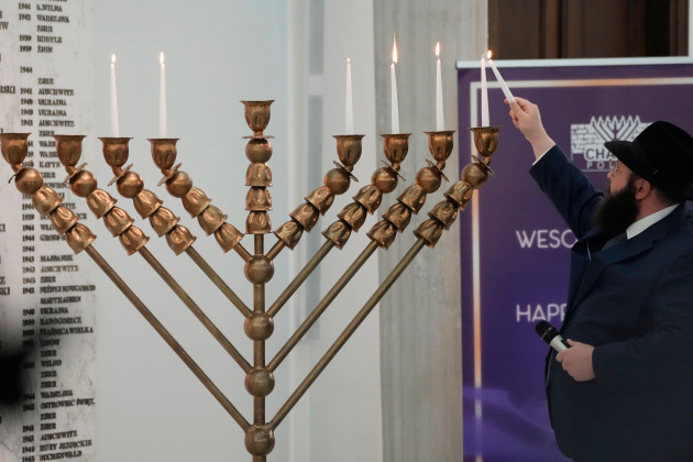 a-rabbi-lights-candles-of-a-menorah-again-after-an-incident-in-which-a-far-right-lawmaker-put-out-the-candles-in-warsaw-poland-on-tuesday-dec-12-2023-the-speaker-of-the-parliament-szymon-holow