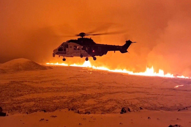 this-image-made-from-video-provided-by-the-icelandic-coast-guard-shows-its-helicopter-flying-near-magma-running-on-a-hill-near-grindavik-on-icelands-reykjanes-peninsula-sometime-around-late-monday-d