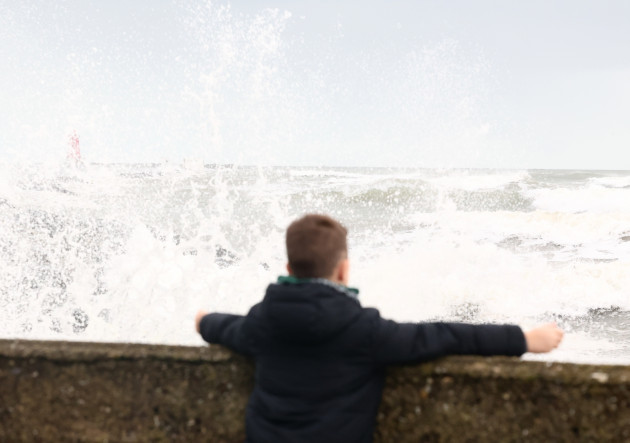 Members of the public watch the crashing waves at Poolbeg in Dublin today