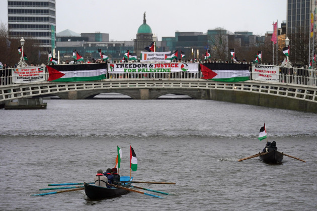 boats-flying-the-flag-of-palestine-make-their-way-along-the-river-liffey-beneath-supporters-of-the-ireland-palestine-solidarity-campaign-taking-part-in-a-vigil-on-the-hapenny-bridge-in-dublin-pictu
