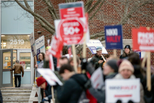 a-voter-enters-a-polling-site-to-cast-their-ballot-in-the-new-hampshire-presidential-primary-in-manchester-n-h-tuesday-jan-23-2024-as-candidate-supporters-campaign-outside-ap-photodavid-gold