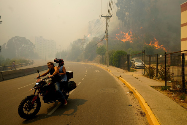 residents-evacuate-on-a-motorcycle-as-smoke-caused-by-forest-fires-fill-the-sky-and-flames-spread-into-vina-del-mar-chile-saturday-feb-3-2024-officials-say-intense-forest-fires-burning-around-a