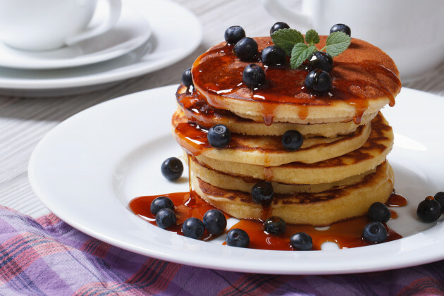 Pastel americano con frambuesas y jarabe de arce en un plato blanco horizontal