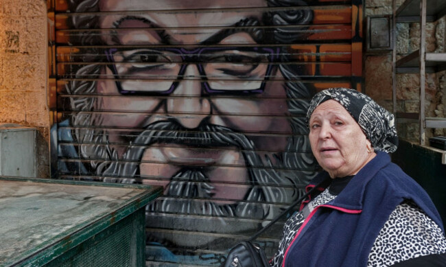 an-israeli-woman-sits-next-to-a-painted-closed-shutters-of-a-shop-depicting-convicted-spy-for-israel-jonathan-pollard-in-mahane-or-machane-yehuda-market-often-referred-to-as-the-shuk-an-open-air-m