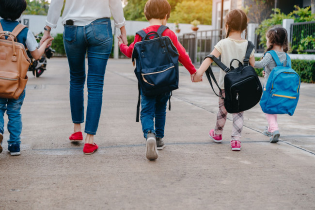 motherandpupilandkidsholdinghandsgoingtoschool