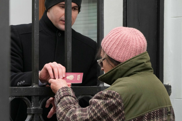 Un agent de sécurité de l'ambassade de Russie vérifie le passeport de la femme russe qui faisait la queue devant l'ambassade de Russie à Varsovie en Pologne, dimanche 17 mars 2024-pour-voter-le dernier jour des Trois jours
