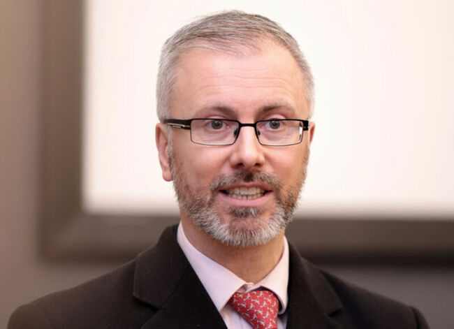 Roderic O'Gorman wearing a dark jacket, light shirt and red tie.