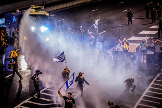 tel-aviv-israel-30th-mar-2024-an-israeli-protestor-holds-up-his-flag-as-he-is-being-targeted-by-a-police-water-canon-during-a-protest-in-tel-aviv-saturday-march-30-2024-on-saturday-tens-of-thou