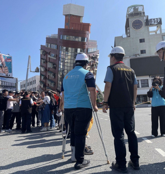 in-this-photo-released-by-the-hualien-city-government-government-workers-and-journalists-are-seen-near-firefighters-working-near-a-leaning-building-in-the-aftermath-of-an-earthquake-in-hualien-easte