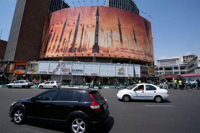 vehicles-drive-past-an-anti-israeli-banner-showing-missiles-being-launched-in-a-square-in-downtown-tehran-iran-friday-april-19-2024-iran-fired-air-defenses-at-a-major-air-base-and-a-nuclear-site